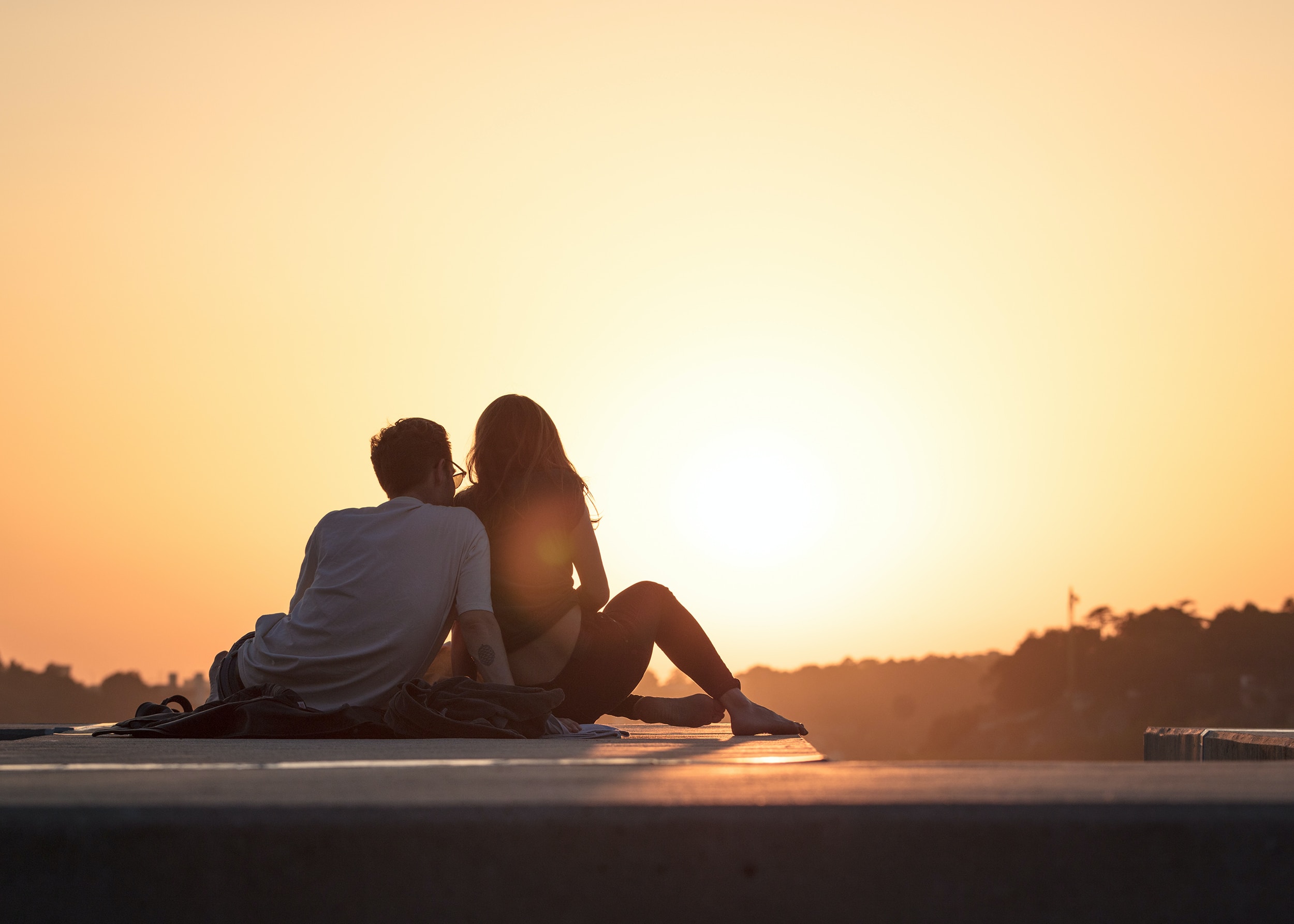 Couple sitting together in Sunset illustrates article about marriage and money
